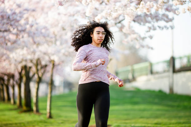 istock Woman Jogging In Spring Tree Blooming City Waterfront 1309991158