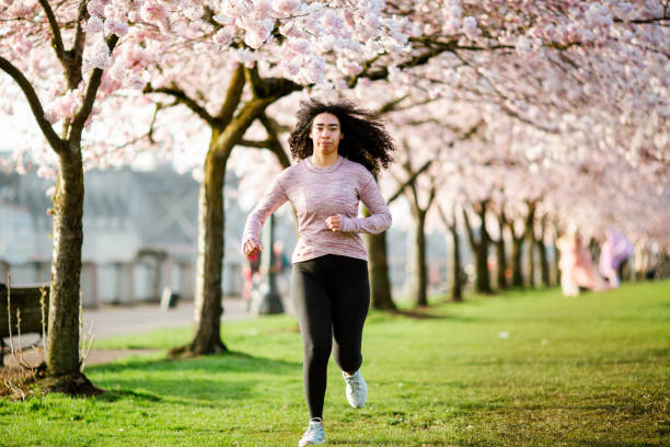 istock Woman Jogging In Spring Tree Blooming City Waterfront 1309991165