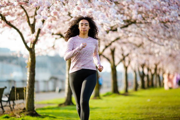 istock Woman Jogging In Spring Tree Blooming City Waterfront 1309991167
