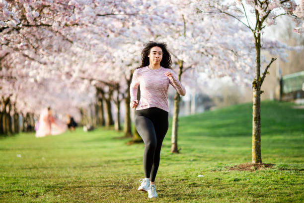 istock Woman Jogging In Spring Tree Blooming City Waterfront 1309991173