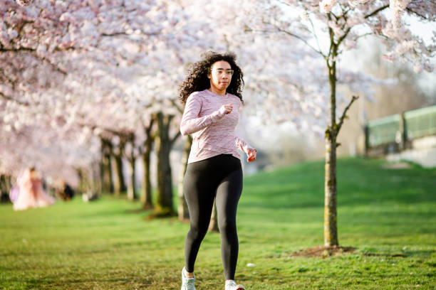 istock Woman Jogging In Spring Tree Blooming City Waterfront 1309991184