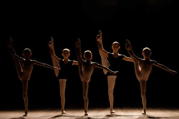 istock Flexible ballerinas stretch on a dark lighted scene 1309991216