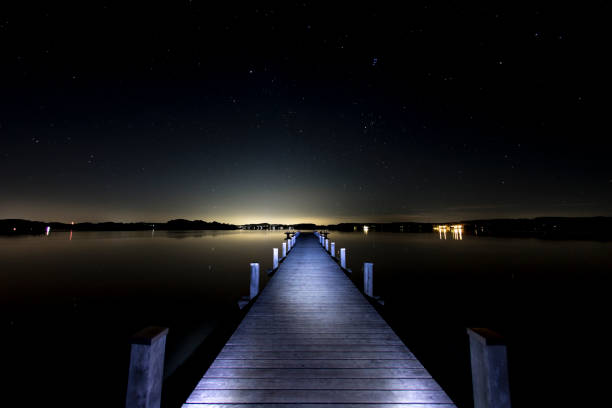view over the lake Woerthsee, Bavaria, Germany, with a illuminated jetty and above the bright and starry night sky