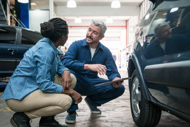 meccanico di auto che parla con il cliente - car examining mechanic auto mechanic foto e immagini stock