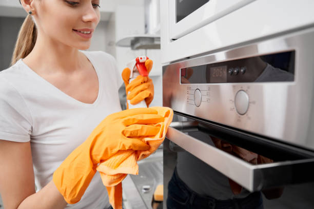 istock Smiling young woman cleaning oven with detergent. 1309993272
