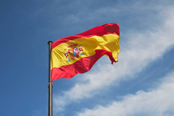 istock Spanish flag flying on a large black mast against a blue sky. 1309994347
