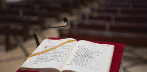 leggio di marmo con un feltro rosso e una bibbia con alcuni banchi sullo sfondo in una chiesa - church altar indoors dark foto e immagini stock