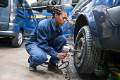 Female car mechanic changing wheel