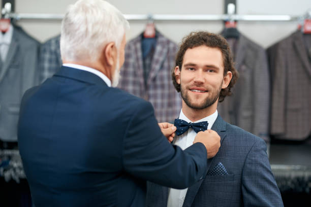 istock Two elegant men smiling and choosing bow tie. 1309995344