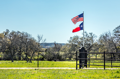 USA flag and the Texas flag waving together in the hill country