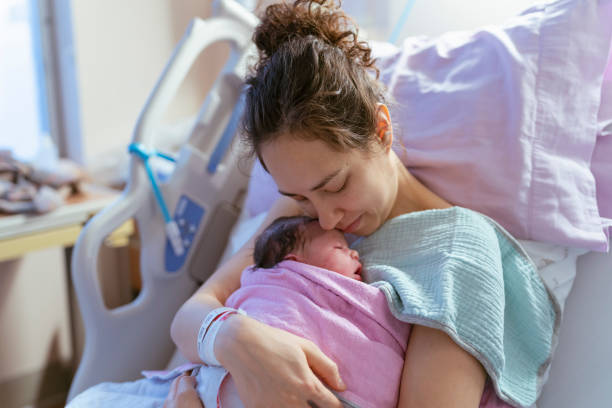 смешанная раса мать snuggling новорожденных после родов - delivery room стоковые фото и изображения