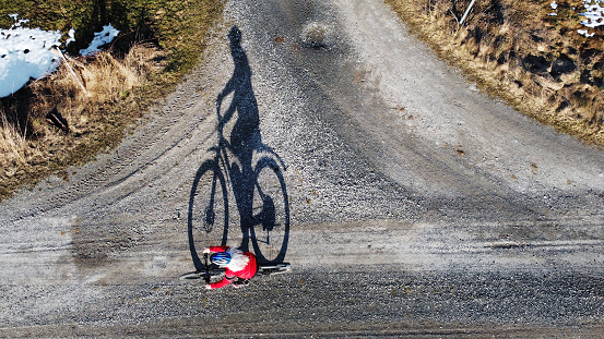 Aerial shot with drone of female cyclist on road with shadow