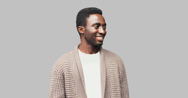 retrato de un hombre africano sonriente feliz mirando hacia otro lado en un fondo gris - cardigan men african ethnicity african descent fotografías e imágenes de stock