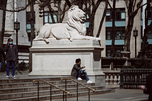 Manhattan, New York City, USA - March, 29.Young black man Eating Takeaway lunch Outdoors in New York City while sitting on stairs near the New York Public Library.