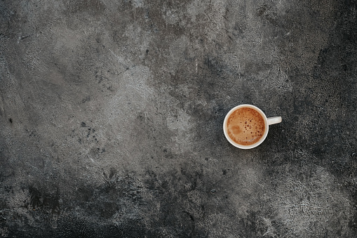 Single Cup of coffee espresso on a dark gray rustic background. Coffe break top view with copy space text
