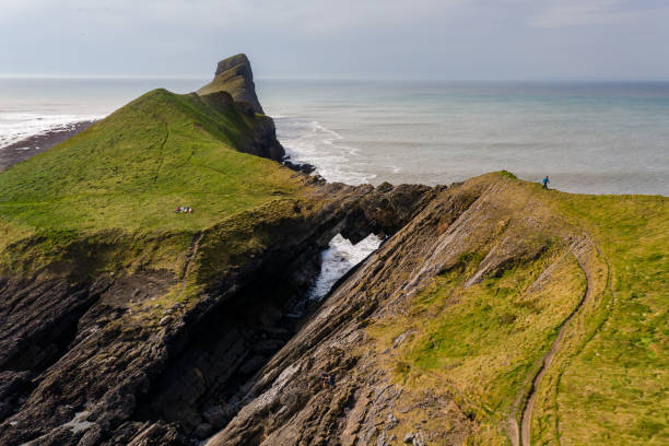 Aerial view of a natural archway on a spectacular rocky coastline (Worm's Head, Wales) Aerial view of a natural rock arch on a spectacular coastline (Worms Head, Wales, UK) gower peninsular stock pictures, royalty-free photos & images