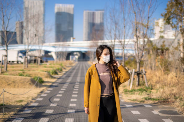 istock Young woman in protective face mask walking in waterfront public park 1310011667