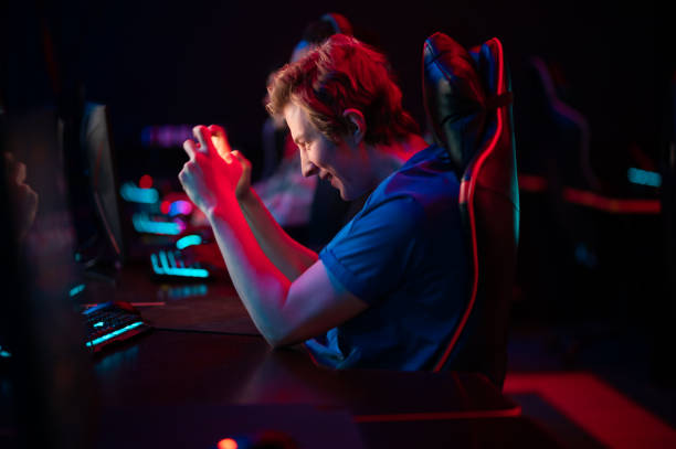 A heavy emotional game on a smartphone performed by a caucasian guy at a computer and in a gaming chair A heavy emotional game on a smartphone performed by a caucasian guy at a computer and in a gaming chair. sportsman professional sport side view horizontal stock pictures, royalty-free photos & images