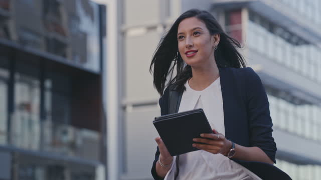 4k video footage of a young businesswoman using a digital tablet while walking in the city