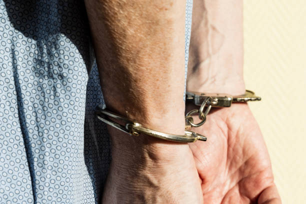Hands of criminal in handcuffs stock photo
