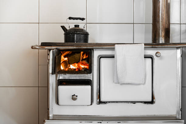 Wood burning stove Image with fire flames inside a white wood burning stove and a black kettle back boiler wood burner stock pictures, royalty-free photos & images