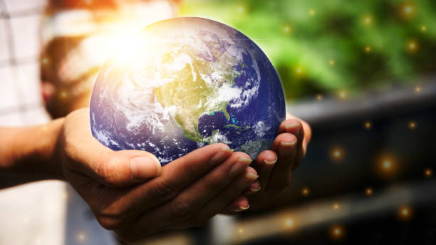 istock A woman's hand holding a globe and there is an orange light spot. 1310018154