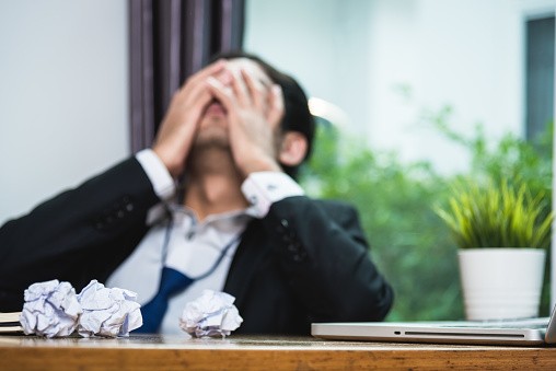 Upset businessman depressed strain by working in office, focus paper