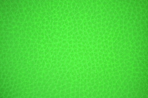 Fragment of natural leather of rough dressing, artificially dyed, acid-green light color. Background, pattern, texture.