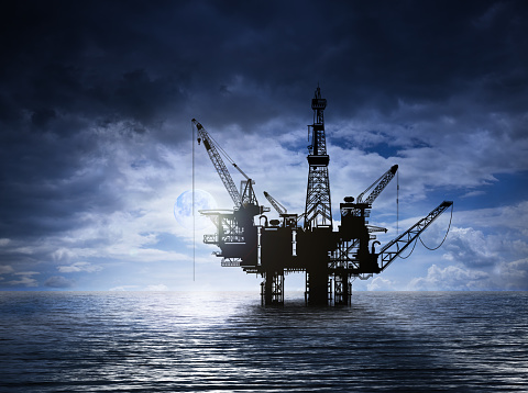 Offshore platform with drilling rig petroleum pump in the ocean at night