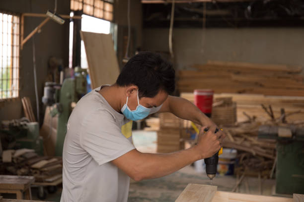 istock Close-up of carpenter using electric drill in workshop and routing out holes Cabinetmaker drilling wood on table. Joinery work on the production and renovation of wooden furniture. Small Business 1310032514
