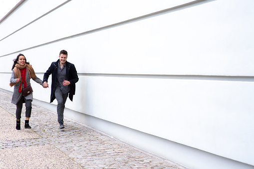 a man and a woman holding hands run along a wall