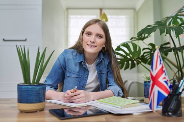 istock UK learning English online. Female student remotely looking at webcam 1310036473