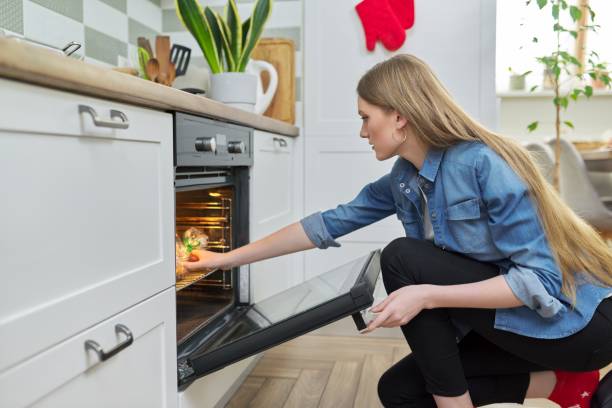 istock Young woman putting marinated chicken in baking bag in oven 1310036583