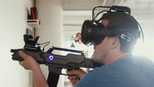 Guy playing VR sniper game with gun and glasses
