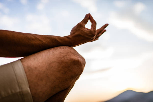 young man preforms yoga in mountains at sunset - zen like nature breathing exercise sitting imagens e fotografias de stock