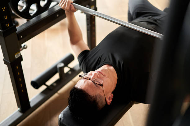 asian man doing bench press in training gym - weight training weight bench weightlifting men imagens e fotografias de stock