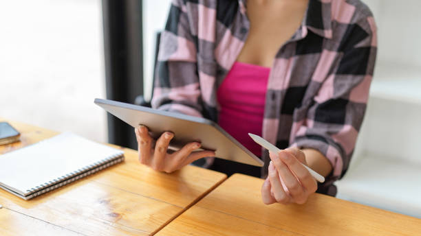 istock Close up view of female hands using digital tablet while sitting at the table in cafe 1310046493