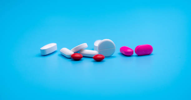 White and pink tablets pill spread on blue background with copy space. Pharmacy web banner. Pharmaceutical industry. Round and oval tablets pills. Prescription drugs. Sample pills for clinical trial. White and pink tablets pill spread on blue background with copy space. Pharmacy web banner. Pharmaceutical industry. Round and oval tablets pills. Prescription drugs. Sample pills for clinical trial. hydroxide stock pictures, royalty-free photos & images