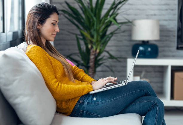 istock Pretty young woman working with her laptop while sitting on couch at home. 1310046617