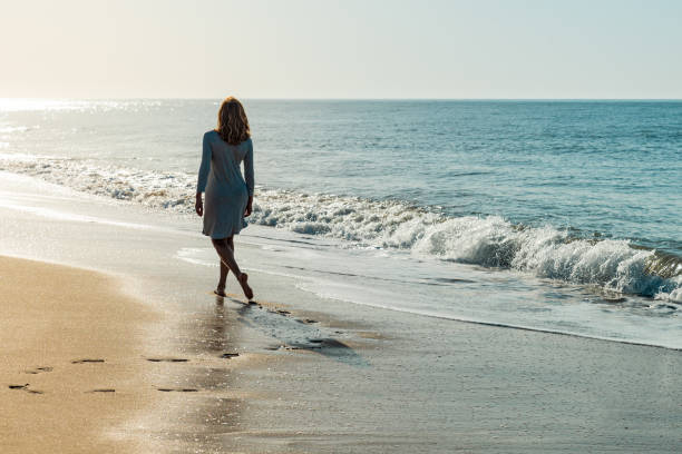 istock Woman walking on the beach looking at the sun 1310047855