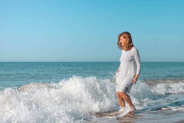 istock Woman on the beach playing in the waves 1310047921