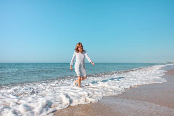 istock Woman on the beach playing in the waves 1310047927