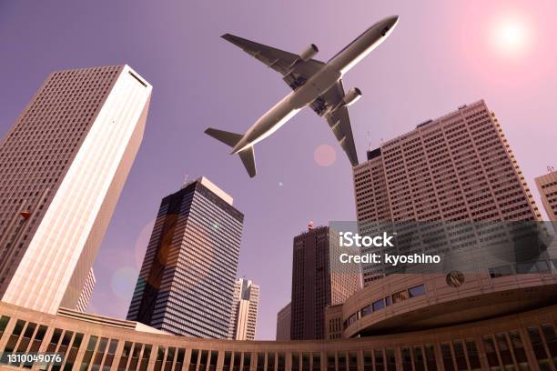Airplane Flying Over A Skyscrapers At Dusk Stock Photo - Download Image Now - Japan, Landing - Touching Down, Airplane