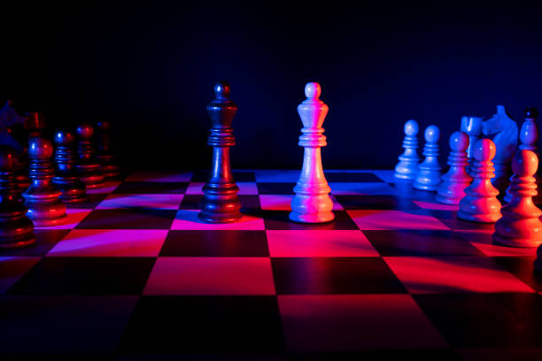 Chess figures on a chessboard. Studio neon lights, blue, red, pink and purple. Focus on king