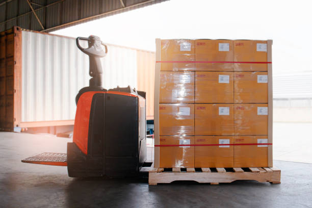 istock Electric Forklift Pallet Jack with Package Boxes on Pallet at Warehouse. Cargo Container Truck Parked Loading at Dock Warehouse. Delivery Service. 1310052538