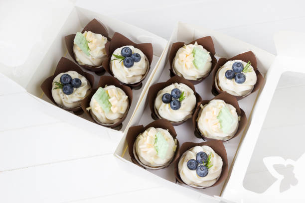 istock Cupcakes  with cream cheese and fresh blueberries, white paper box, white background. Berry cupcakes in delivery box. Sweet food delivery 1310054518