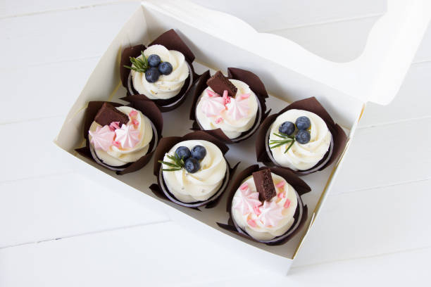 istock Cupcakes  with cream cheese and fresh blueberries, white paper box, white background. Berry cupcakes in delivery box. Sweet food delivery 1310054519