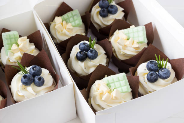 istock Cupcakes  with cream cheese and fresh blueberries, white paper box, white background. Berry cupcakes in delivery box. Sweet food delivery 1310054527