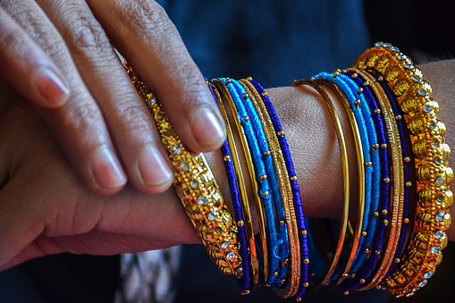 Stock photo of a hand of Indian women wearing colorful bangles with gold Indian design bracelet, picture captured at the time of Indian wedding season at Bangalore Karnataka India.