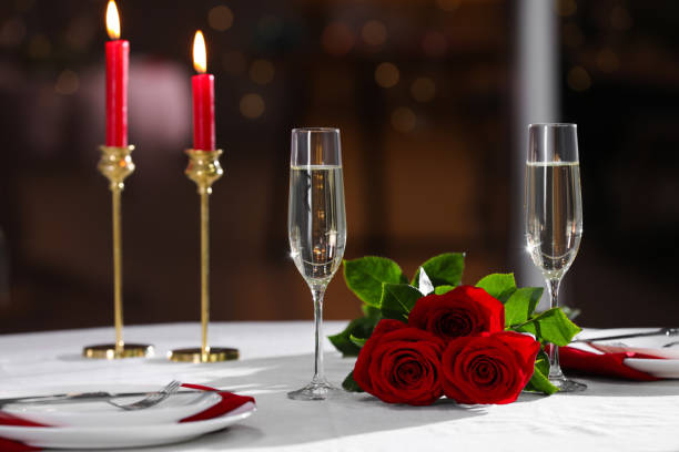 istock Romantic dinner table setting with glasses of champagne and red roses in restaurant 1310057560